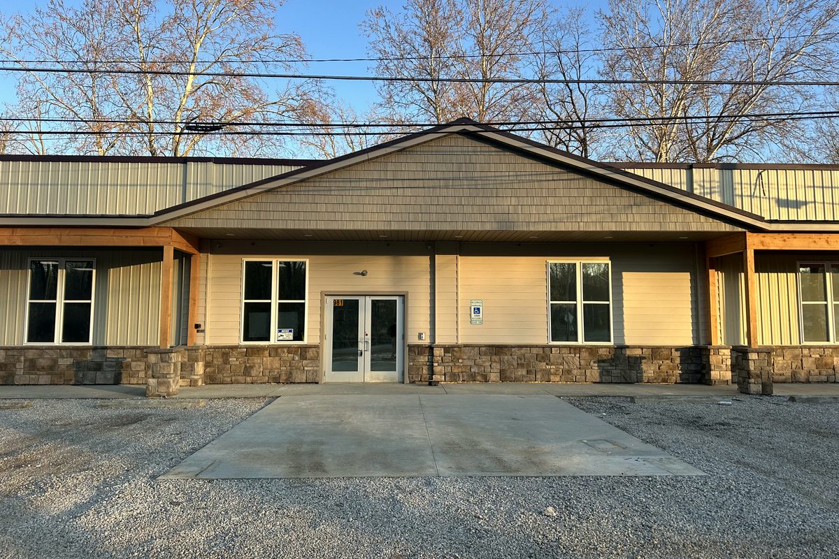 The front of the Homeward Bound building at 981 Grosjean Road: cream siding, a stone base, timber posts, and glass double doors at the centre.